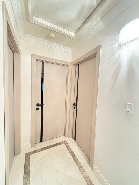 YL-G beige doors with black glass installed in a luxury hallway with marble flooring