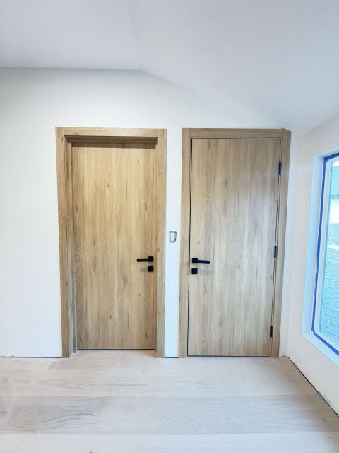 Two SL Golden Oak doors installed side by side - warm wood tones in a modern hallway